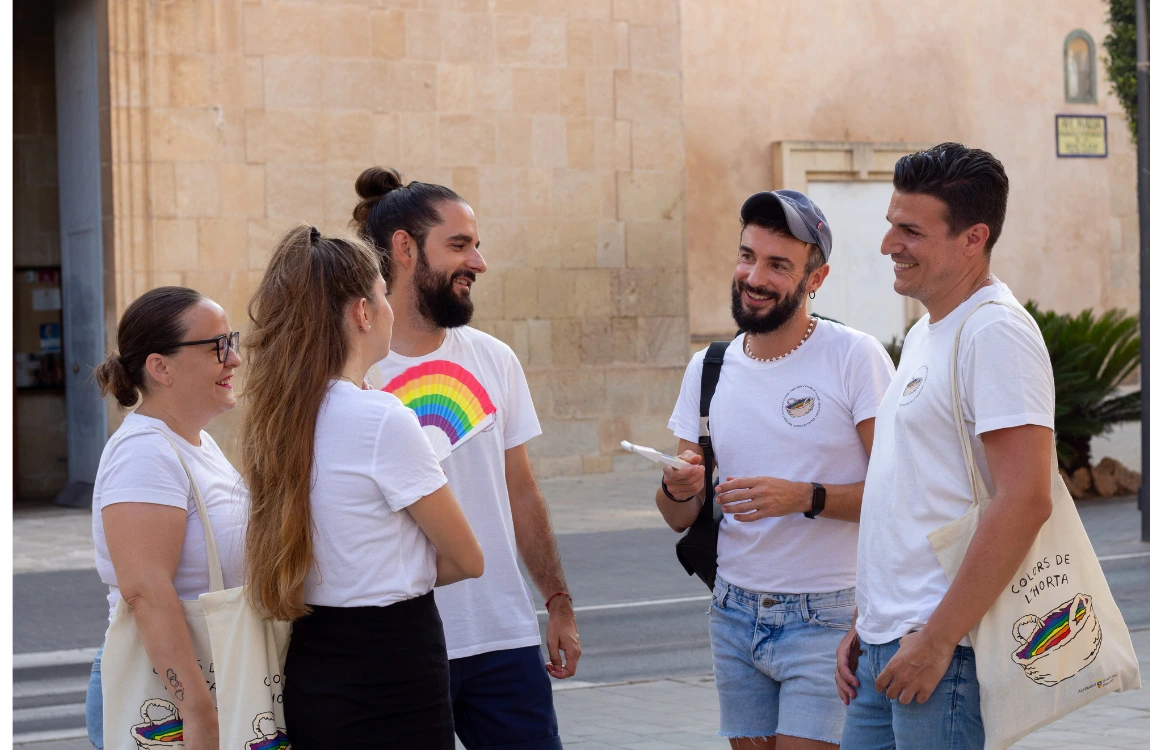 Cinco miembres de Colors de l'Horta en la plaza del ayuntamiento de Sant Joan hablando.