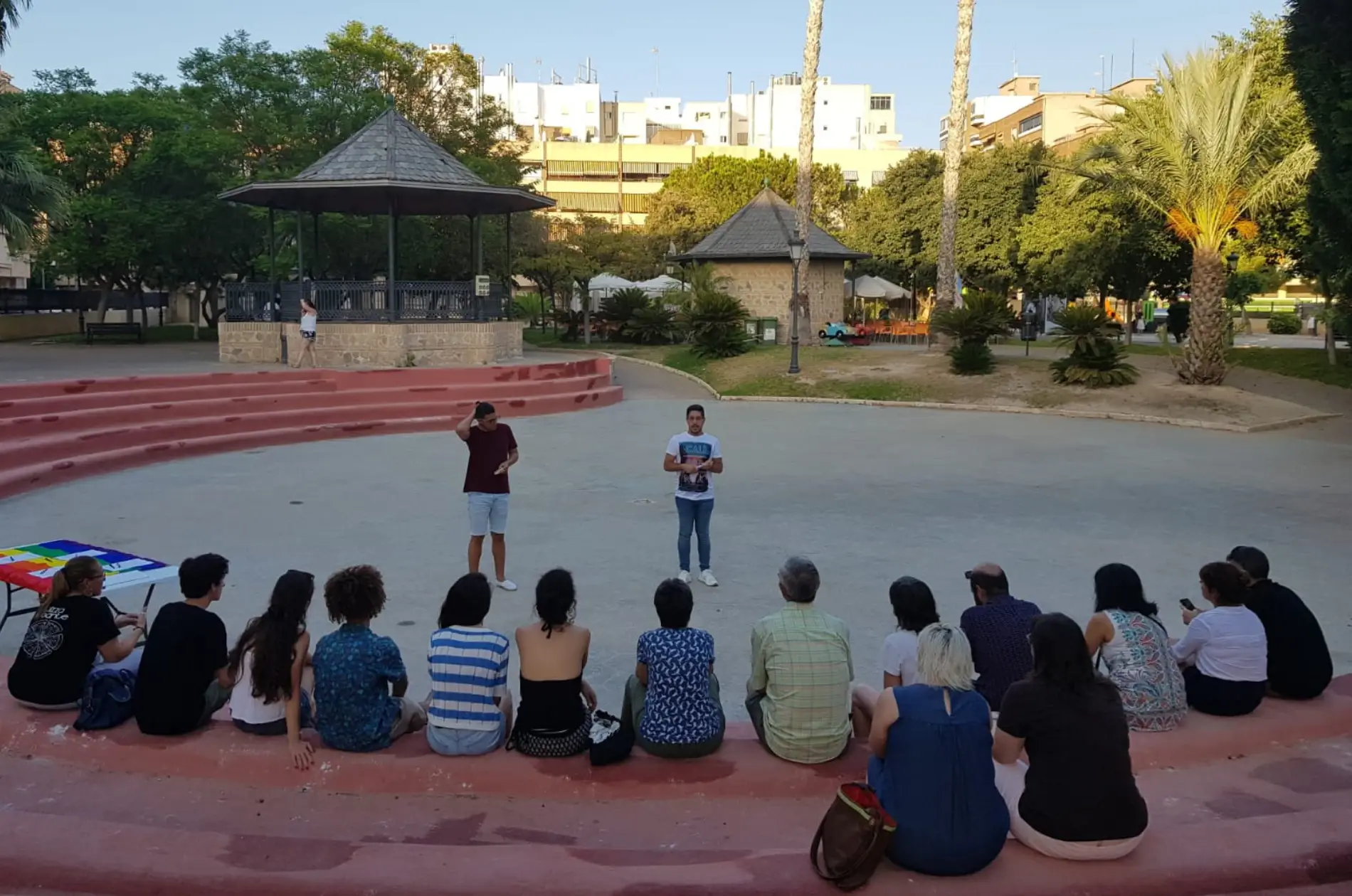 En el Parque Nuevo de Sant Joan, unas 20 personas reunidas en semicírculo mirando a dos personas que les hablan de pie.