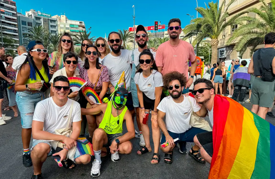 15 personas posando con banderas LGTBIQ posando delante de la plaza de los Luceros de Alicante con motivo del Orgullo.