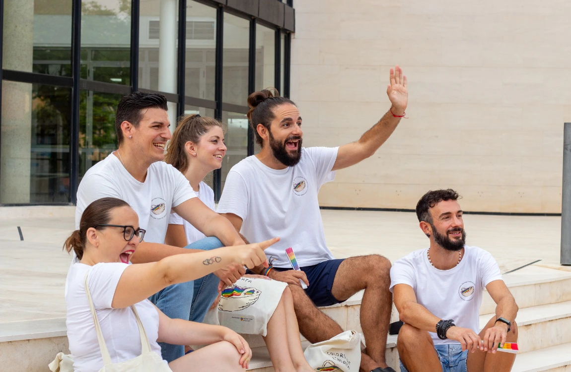 Parte de la junta directiva sentada en las escaleras de la Casa de Cultura de Sant Joan. Salen sonrientes y algunos saludan a alguien a lo lejos.