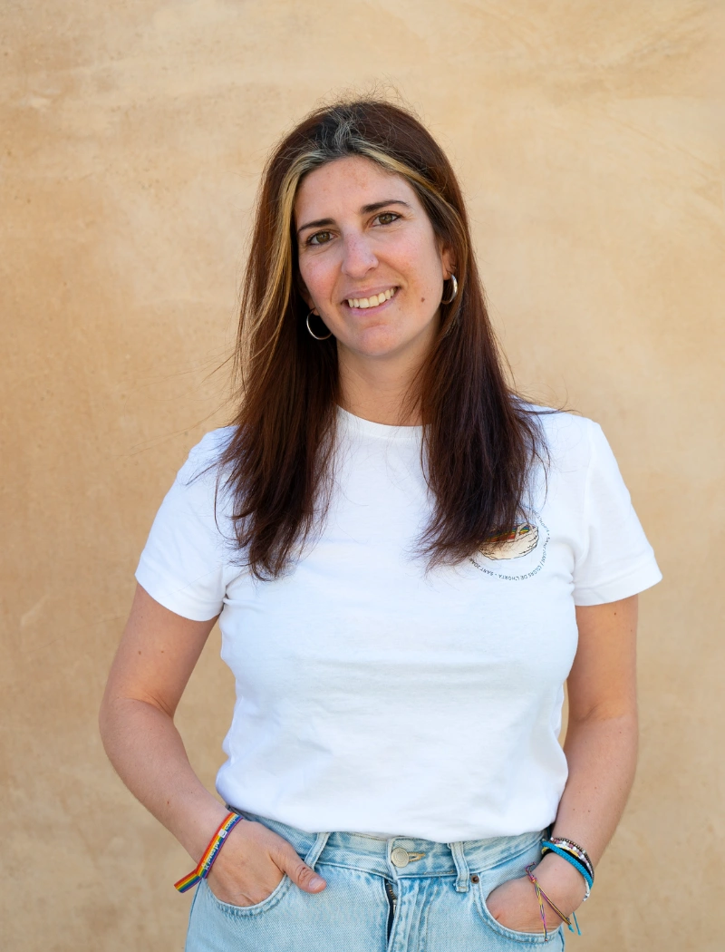Fotografía de Sofía Nadal. Una mujer de unos 30 años con pelo largo castaño y dos mechas de color rubio. Lleva la camiseta de colores del horta en blanco.